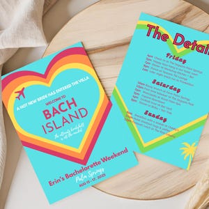 Puede incluir: Dos invitaciones turquesas para despedida de soltera con diseños coloridos de corazón y arcoíris. Una tarjeta dice "Bach Island" y la otra enumera los detalles del fin de semana. Las invitaciones están sobre una bandeja de madera.