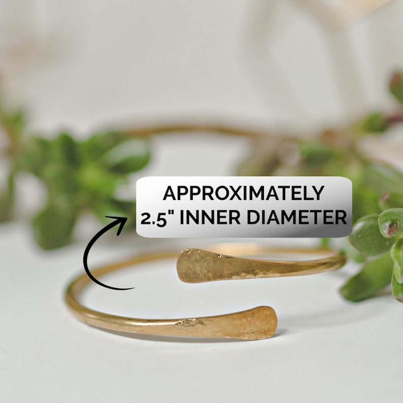 May include: A gold-toned metal bangle bracelet with a hammered finish. The bracelet is open and has a 2.5" inner diameter.  "Approximately 2.5" Inner Diameter" is written on a white label.