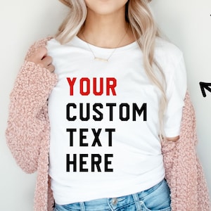 May include: White t-shirt with the text "YOUR CUSTOM TEXT HERE" in black and red lettering.  Add your own text to personalize this shirt.