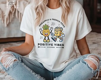 Puede incluir: Camiseta blanca con un gráfico de una piña y papas fritas con el texto "Pineapple & French Fries Positive Vibes #IYFStrong".