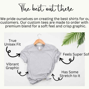 May include: A gray t-shirt on a hanger with text that says "True Unisex Fit", "Vibrant Graphic", "Feels Super Soft", and "Has Some Stretch to it".