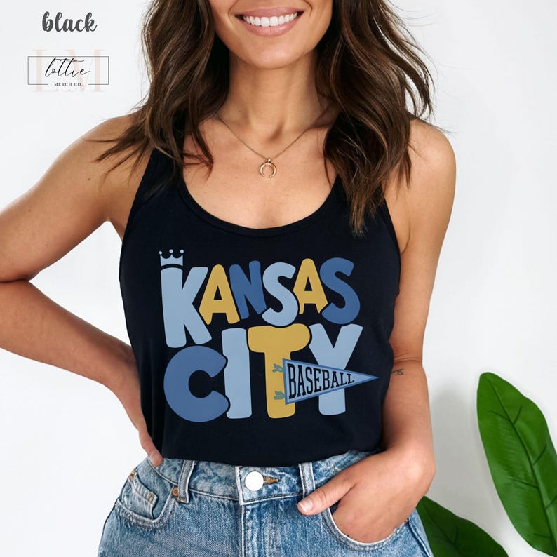 Op de afbeelding: Zwarte tanktop met de woorden "Kansas City" in blauwe en gele blokletters. Een wimpel met de tekst "Baseball" staat onder het woord "City". De tanktop wordt door een persoon gedragen.