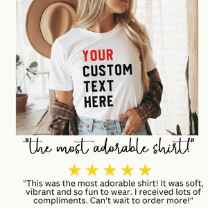 May include: White t-shirt with the text "YOUR CUSTOM TEXT HERE" in black and red lettering. The shirt is being worn by a person with long blonde hair and a brown hat. The text "the most adorable shirt!" is written below the image.