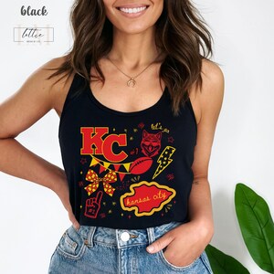 May include: Black tank top with a red and yellow graphic design. The design includes the letters "KC", a football, a wolf, a lightning bolt, and the words "Kansas City". The tank top also has the text "let's go".