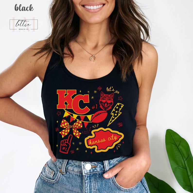 May include: Black tank top with a red and yellow graphic design. The design includes the letters "KC", a football, a wolf, a lightning bolt, and the words "Kansas City". The tank top also has the text "let's go".