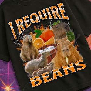 May include: Black t-shirt with the text "I REQUIRE BEANS" in orange, featuring capybaras, oranges, and a bowl of beans. The shirt is part of the "Mildly Perturbed" collection, with a retro VHS aesthetic.