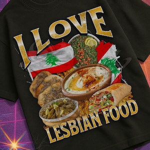 Pu&ograve; includere: T-shirt nero con la scritta dorata "I LOVE LESBIAN FOOD". La maglietta presenta una grafica di cibo libanese e una bandiera. La maglietta fa parte della collezione "Mildly Perturbed".