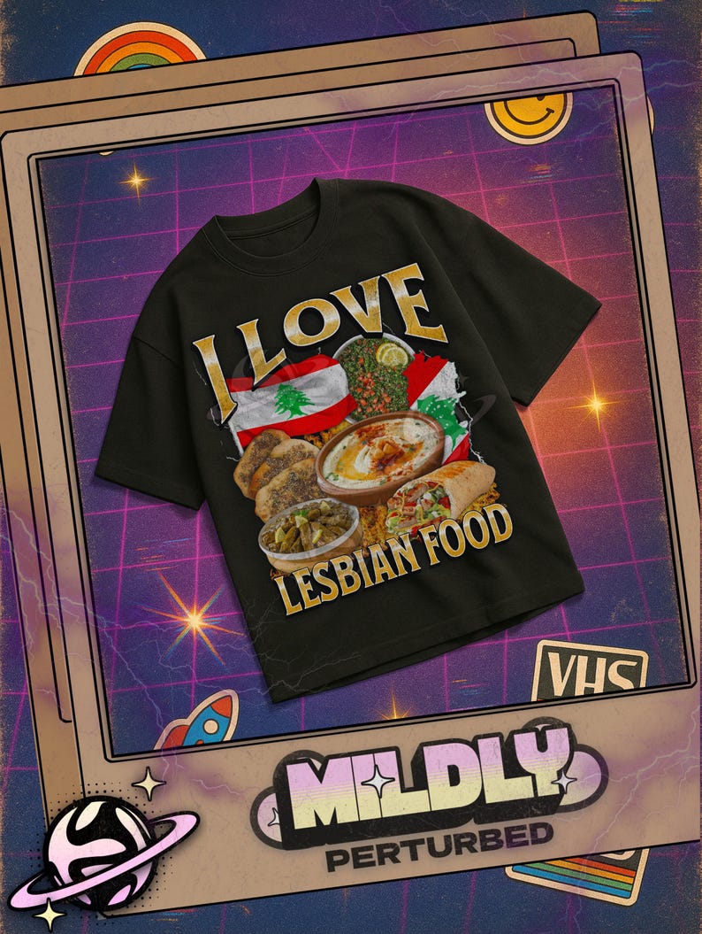 Pu&ograve; includere: T-shirt nero con la scritta dorata "I LOVE LESBIAN FOOD". La maglietta presenta una grafica di cibo libanese e una bandiera. La maglietta fa parte della collezione "Mildly Perturbed".