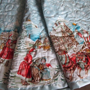 Puede incluir: Una falda de &aacute;rbol de Navidad acolchada de color azul claro con una escena invernal que presenta a Pap&aacute; Noel, renos y ni&ntilde;os. La falda tiene un borde de sat&eacute;n y un patr&oacute;n de copos de nieve.