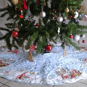 Puede incluir: Un &aacute;rbol de Navidad decorado con adornos y una falda de &aacute;rbol acolchada azul claro. La falda del &aacute;rbol presenta una escena invernal con ilustraciones rojas, blancas y marrones. Un cascanueces est&aacute; cerca.