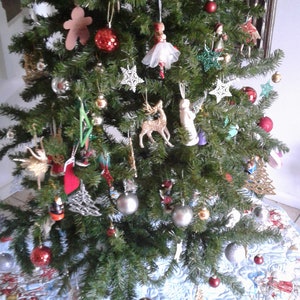 Puede incluir: Un &aacute;rbol de Navidad decorado con varios adornos, incluyendo bolas rojas y plateadas, decoraciones en forma de estrella y peque&ntilde;as figuras. El &aacute;rbol se encuentra sobre una falda de &aacute;rbol azul claro con un dise&ntilde;o de escena invernal.