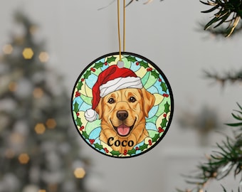 May include: Round Christmas ornament featuring a golden Labrador Retriever wearing a Santa hat. The dog's name, "Coco," is printed below. The ornament has a black border and is decorated with holly and a stained-glass-style background.