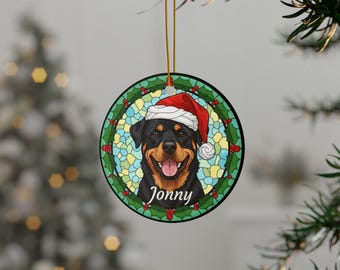 May include: Round Christmas ornament featuring a Rottweiler wearing a Santa hat. The dog's portrait is set against a stained-glass style background with the name "Jonny" below. The ornament is trimmed with a gold string for hanging.
