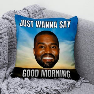 Puede incluir: Un cojín decorativo cuadrado con un retrato de un hombre sonriente sobre un fondo de cielo azul y amarillo. El texto "JUST WANNA SAY GOOD MORNING" está impreso en letras blancas.
