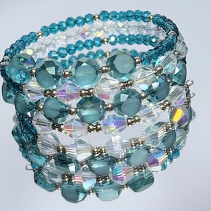 Peut inclure: Un bracelet à plusieurs rangs avec des perles de cristal bleu sarcelle et transparentes. Le bracelet a un design en spirale avec des accents métalliques argentés. Les cristaux reflètent la lumière, créant un effet scintillant. Ce bijou convient à diverses occasions.
