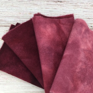 May include: Four fabric squares in shades of burgundy and red, with a gradient effect from dark to light. The fabric has a soft, textured surface.