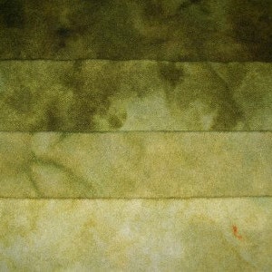 May include: Four horizontal strips of fabric in shades of green, with a subtle tie-dye pattern. The fabric is soft and textured, with a slightly uneven surface.