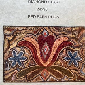 May include: A rectangular rug with a central floral design. The rug features a large, stylized flower in shades of red, peach, and brown, with blue star-shaped flowers on either side. The rug measures 24x36 inches and is labeled "Diamond Heart" and "Red Barn Rugs."