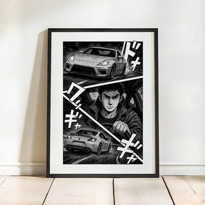 Puede incluir: Impresión enmarcada en blanco y negro que representa una escena de carreras de coches al estilo manga. La obra de arte muestra a un conductor en un coche, con otros dos coches corriendo arriba y abajo. Texto japonés y líneas de velocidad.