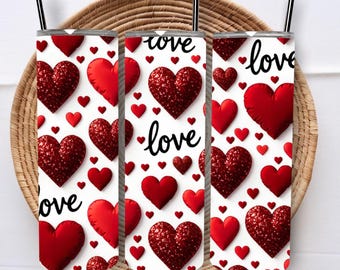 May include: Three white tumblers with a red heart pattern and the word "love" in black script. The hearts vary in size and texture, with some appearing glittery. Each tumbler has a black straw.