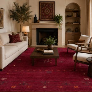 Puede incluir: Una alfombra rectangular grande de color rojo carmesí intenso con un patrón sutil de pequeños motivos geométricos y formas botánicas estilizadas en tonos apagados de oro, marrón y crema, que cubre el suelo de una sala de estar.
