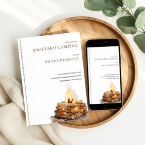 Puede incluir: Una invitación blanca y un teléfono inteligente muestran un diseño de invitación "Backyard Camping". La invitación presenta texto y una ilustración de acuarela de una fogata. La invitación está sobre una bandeja de madera con vegetación.