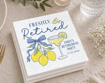 May include: A stack of white square paper napkins featuring a blue printed design of lemons with a blue ribbon, a cocktail glass, and the text "FRESHLY RETIRED", "EMILY'S RETIREMENT PARTY", and the date "12.23.2026" in a dark blue script and serif font.