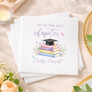 May include: White square paper napkins with a graduation theme. The napkins feature a stack of books with a graduation cap, floral accents, and the text "On to the next chapter" and a name. The design includes butterflies and bees.