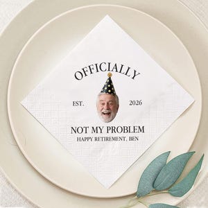 Peut inclure: Une serviette en papier blanche avec un motif en losanges, avec le texte "OFFICIALLY" au-dessus d'un visage souriant portant un chapeau de fête. En dessous, on peut lire "NOT MY PROBLEM HAPPY RETIREMENT, BEN".