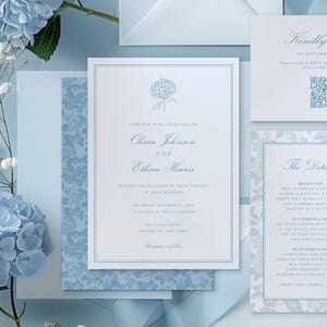 May include: Elegant light blue wedding invitations with floral accents. The invitation suite includes a main invitation, RSVP card, and details card. The main invitation features the names Olivia Johnson and Ethan Harris.