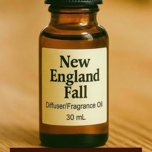 May include: A brown glass bottle with a black cap, labeled "New England Fall Diffuser/Fragrance Oil 30 mL." The label is cream-colored with black text. The words "New England Fall" are also displayed in a brown banner at the bottom.