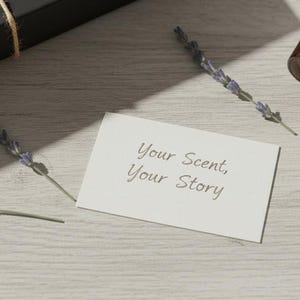 Puede incluir: Exhibici&oacute;n de productos de aromaterapia con una botella de vidrio marr&oacute;n, un tap&oacute;n de madera y ramitas de lavanda. Tambi&eacute;n hay una tarjeta blanca con el texto "Your Scent, Your Story". Los art&iacute;culos est&aacute;n sobre una superficie de madera clara.