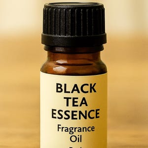 May include: A small amber glass bottle of Black Tea Essence fragrance oil with a black cap. The label displays the product name and the volume, 5mL. The bottle is set against a warm, neutral background.