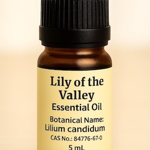May include: A small amber glass bottle of Lily of the Valley essential oil with a black cap. The label displays the product name, botanical name, and other details. The bottle contains 5 mL of oil.