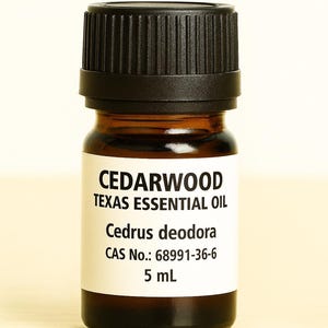 May include: A small amber glass bottle of Cedarwood Texas Essential Oil with a black cap. The label displays the product name, botanical name, and other details. The bottle contains 5 mL of oil.