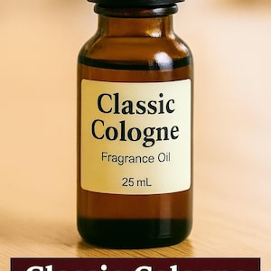 May include: A small, brown glass bottle of Classic Cologne fragrance oil with a black cap. The label reads "Classic Cologne Fragrance Oil 25 mL". The bottle is on a light brown surface.