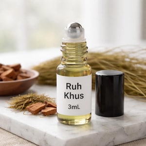 Puede incluir: Una peque&ntilde;a botella de vidrio de perfume Ruh Khus con una tapa de bola rodante plateada y una tapa negra. La etiqueta dice "Ruh Khus 3ml". La botella est&aacute; llena de un l&iacute;quido amarillo claro. La botella est&aacute; sobre una superficie de m&aacute;rmol.