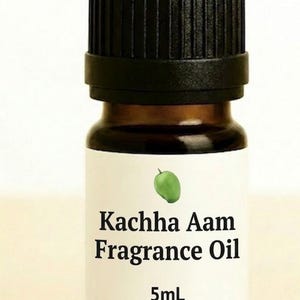 May include: A small brown glass bottle with a black cap, labeled "Kachha Aam Fragrance Oil." The label features a green mango illustration and the text "5mL."