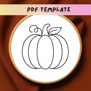May include: A black and white pumpkin outline design on a white background, set within a wooden embroidery hoop. The text "PDF TEMPLATE" is displayed at the top. The design is suitable for embroidery or crafting projects.