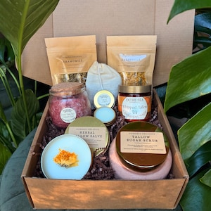 Puede incluir: Una caja de regalo llena de varios productos de cuidado personal. La caja contiene frascos de sal del Mar Muerto, az&uacute;car de canela de sebo batido y exfoliante de az&uacute;car de sebo. Tambi&eacute;n se incluyen sobres de manzanilla y cal&eacute;ndula, y ung&uuml;ento de sebo herbal.