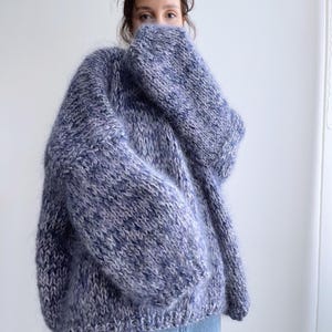 May include: A blue and white fuzzy knit sweater with a loose fit.