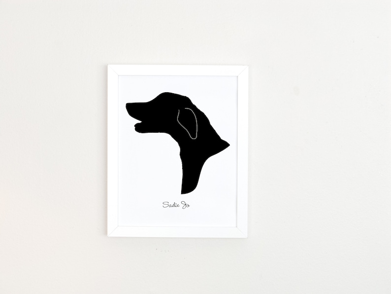 May include: A black and white silhouette of a dog's head in a white frame. The dog's name, "Sadie Jo", is written below the silhouette.