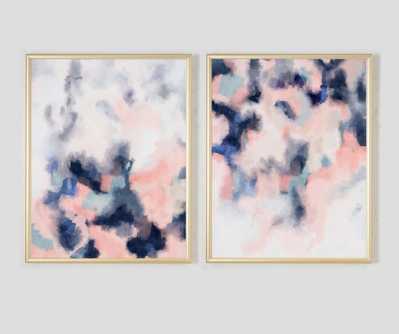 May include: Two abstract paintings in gold frames. The paintings are both pink, blue, and white with a watercolor effect.