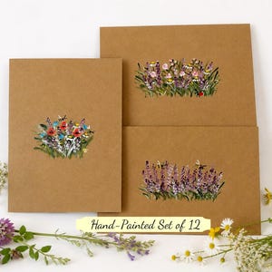 May include: A set of brown kraft paper greeting cards featuring hand-painted floral illustrations. The designs include clusters of colorful wildflowers, lavender sprigs, and small bees. A yellow label with the text Hand-Painted Set of 12 is visible.
