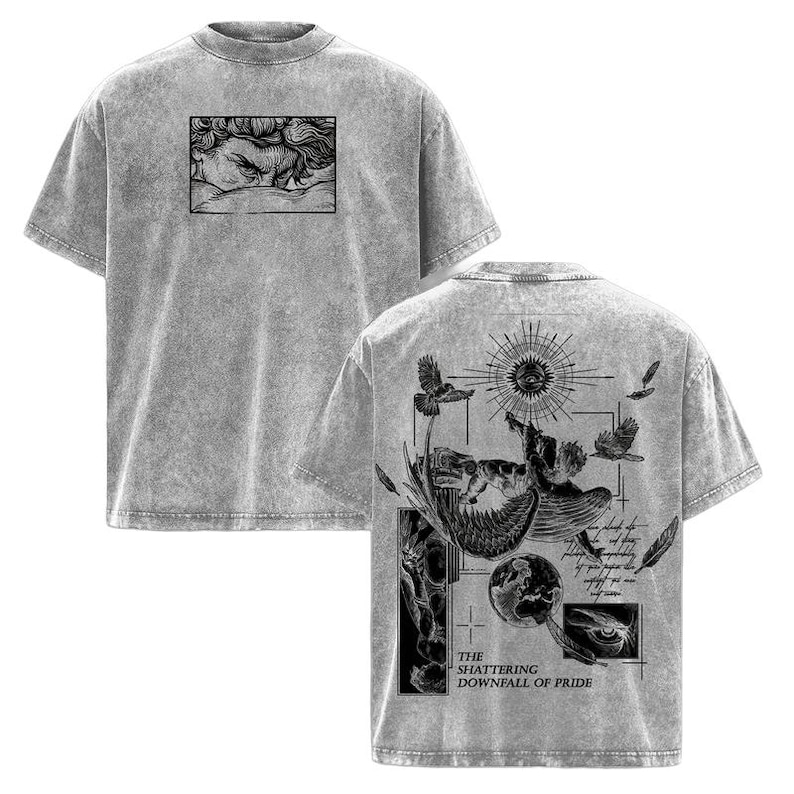 May include: Gray t-shirt with a distressed texture. The front features a black and white illustration of a face. The back displays a detailed graphic with birds, a sun, and the text "THE SHATTERING DOWNFALL OF PRIDE."