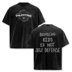 May include: A black acid-wash t-shirt featuring a front graphic of a globe with the text "PALESTINE" and "FREE FREE" and a heart icon. The back of the shirt displays the grey text "BOMBING KIDS IS NOT SELF DEFENSE" in a bold, rounded font.