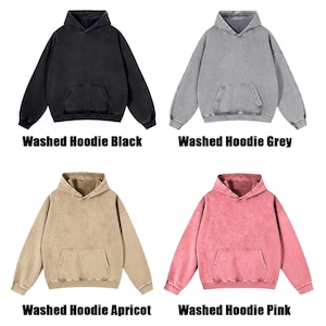 May include: Four washed hoodies in black, grey, apricot, and pink. Each hoodie has a hood and a front pocket. The text "Washed Hoodie" is above each colour name.