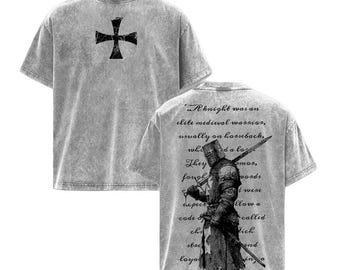 May include: Gray t-shirts with a distressed look. One shirt features a black cross graphic, while the other displays a knight illustration with text. The text on the back of the shirt reads "A knight was an elite medieval warrior..."