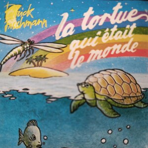Peut inclure: Une illustration colorée d'une tortue nageant dans l'océan. La tortue est verte et jaune avec une carapace brune. L'océan est bleu et des bulles sortent de la bouche de la tortue. Le texte "la tortue qui était le monde" est écrit en arc-en-ciel au-dessus de la tortue.