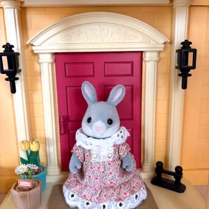 May include: A white ceramic mug with a black handle and the text "But First, Coffee" in a bold, black font. The mug is set against a blurred background, suggesting a cozy setting.